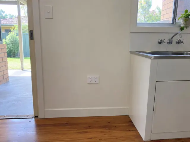Double power point on a plain interior wall beside a kitchen sink and doorway in Cardiff